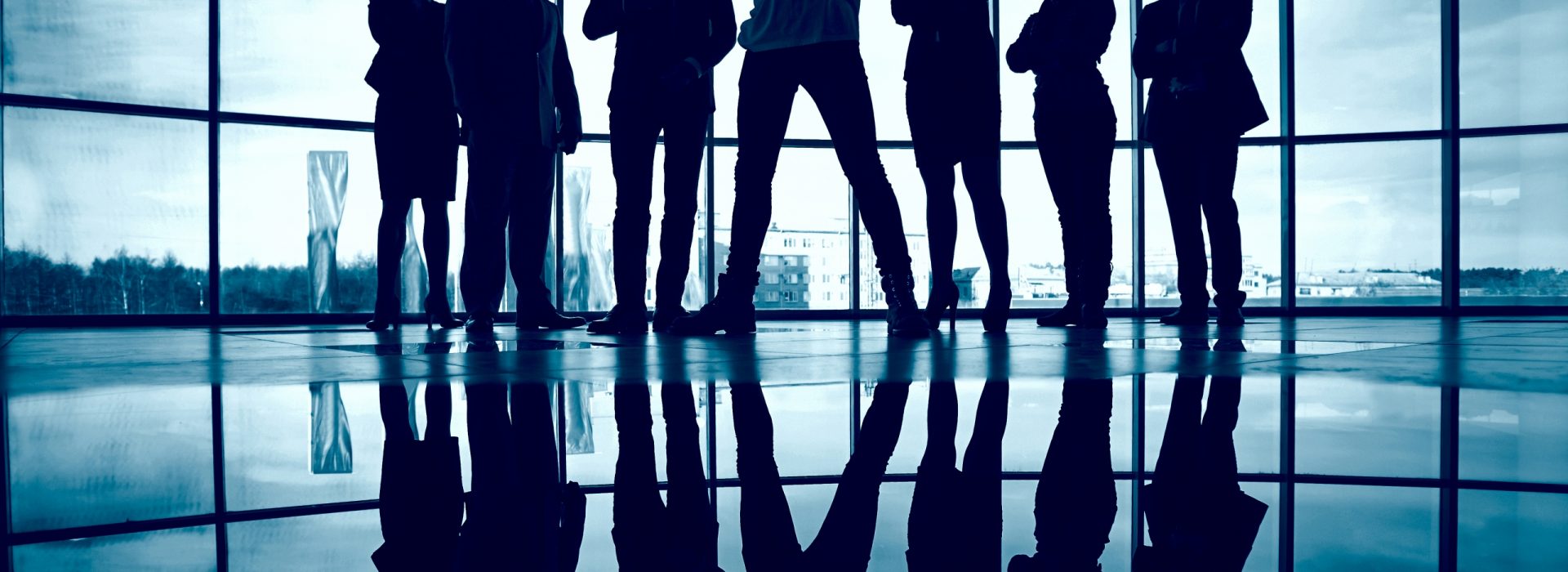 Business team standing against window with leader in front